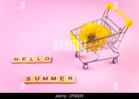 Ciao estate. Carrello con fiori. Fiore giallo su sfondo rosa. Foto Stock