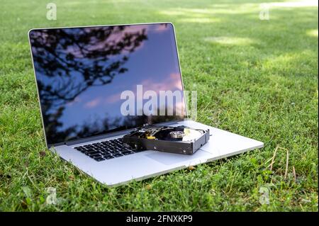 Visualizza su un computer portatile con un disco rigido sull'erba in una giornata di sole. Foto Stock