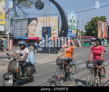 Strada trafficata nel centro di Jaffna con pedoni, scooter autisti, donne che cavalcano biciclette e affissioni pubblicità, Provincia del Nord, Sri Lanka Foto Stock