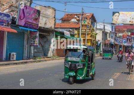 Strada trafficata nel centro di Jaffna con rickshaws auto, biciclette e moto che passa davanti a negozi, Provincia del Nord, Sri Lanka Foto Stock