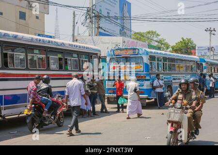 I pedoni che camminano intorno al bus-stand di Jaffna mentre la polizia nelle uniformi di kaki guidano oltre sulla moto, Sri Lanka Foto Stock