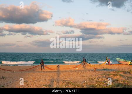 Pescatori sulla spiaggia che tende alle loro reti da pesca poco prima del tramonto, Mullaitivu, Provincia del Nord, Sri Lanka Foto Stock