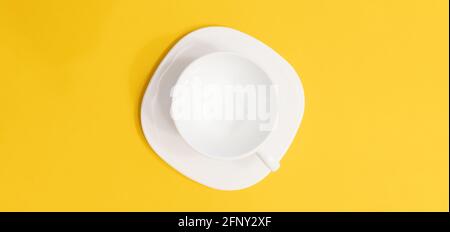Tazza di caffè sul piattino su sfondo giallo vista dall'alto, scatto panoramico con spazio per la copia Foto Stock
