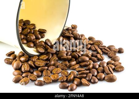 Versare i chicchi di caffè dalle tazze su sfondo bianco Foto Stock