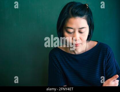 Solitaria donna asiatica sconvolto. Ritratto di infelice donna asiatica. Sfondo di parete greed. Colore regolato. Foto Stock