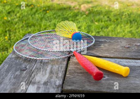 Racchette da gioco di badminton e shuttlecock su un tavolo di legno con verde erba backgroud nel parco in una giornata estiva soleggiato. Concetto di stile di vita attivo. Divertimento Foto Stock