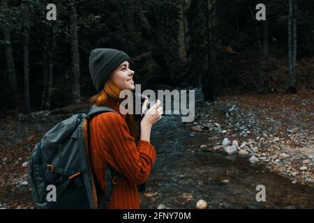 donna con una macchina fotografica vicino a uno stagno in montagna sulla natura e alberi paesaggio forestale Foto Stock