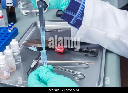 Lo scienziato della polizia tiene una fiala con una traccia di sangue sul tampone per indagare l'omicidio nel laboratorio di criminalità, immagine concettuale Foto Stock