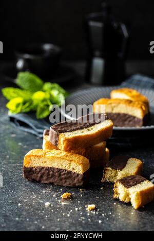 Dessert a fette di spugna. Dolce pan di Spagna con cioccolato su tavola nera. Foto Stock