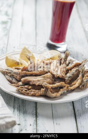 Colpo verticale di acciughe fritte con limoni a fette su a. piastra Foto Stock