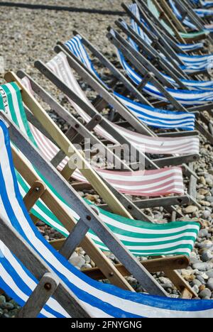 Sedie a sdraio vuote sulla spiaggia di ciottoli presso la località balneare di Beer, Devon, Regno Unito Foto Stock