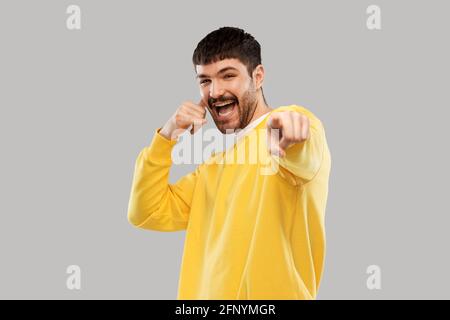 uomo che fa il gesto di chiamata del telefono e punta il dito Foto Stock