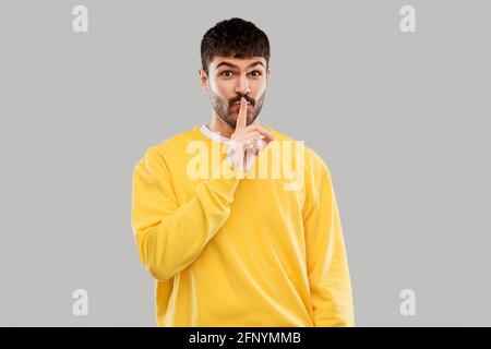 giovane uomo che fa un gesto di hush con un dito sulle labbra Foto Stock