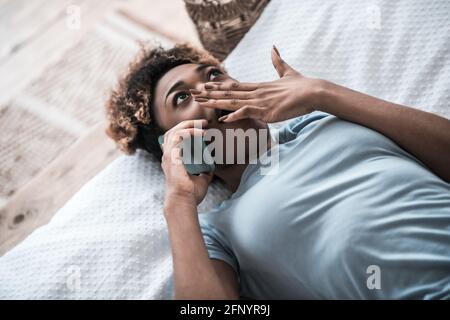 Donna sorpresa con smartphone che copre la bocca con la mano Foto Stock