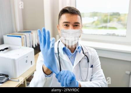 medico in maschera medica indossando guanti in ospedale Foto Stock