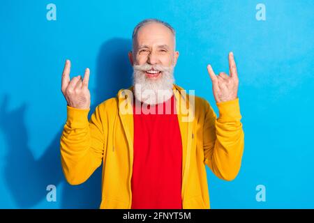 Ritratto fotografico del vecchio uomo che mostra un gesto di metallo pesante isolato su sfondo di colore blu intenso Foto Stock