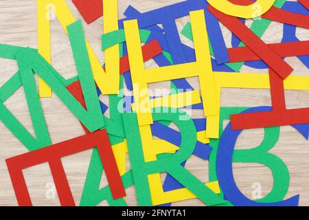 colorate lettere in jumbled, in carta, giacenti su legno Foto Stock