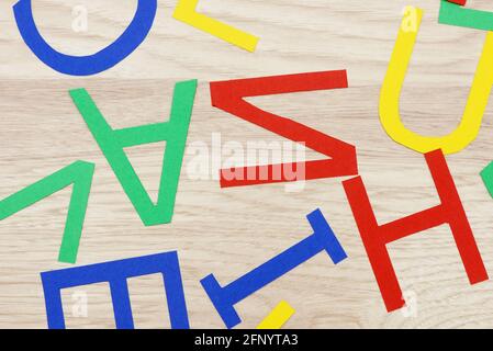 colorate lettere in jumbled, in carta, giacenti su legno Foto Stock