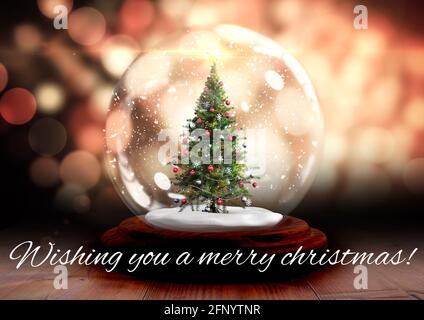 Composizione di augurarvi un allegro testo natalizio sulla neve globo con albero di natale in background Foto Stock