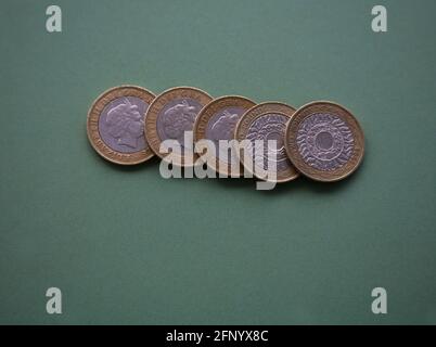 Primo piano cinque monete inglesi Sterling £2 su sfondo verde Foto Stock