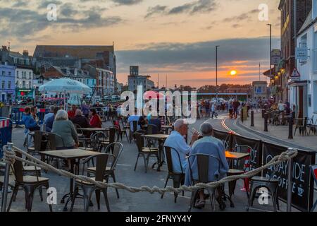 Vista di caffè e bar nel porto vecchio e case sul molo al tramonto, Weymouth, Dorset, Inghilterra, Regno Unito, Europa Foto Stock