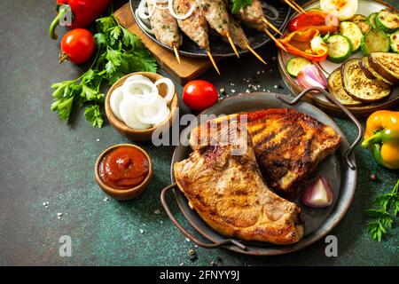 Kebab Kofta fatti in casa, bistecca alla griglia e verdure alla griglia su uno spiedino con verdure e salsa di pomodoro su un piano di pietra scuro. Spazio di copia. Foto Stock