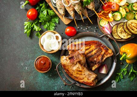 Kebab Kofta fatti in casa, bistecca alla griglia e verdure alla griglia su uno spiedino con verdure e salsa di pomodoro su un piano di pietra scuro. Vista dall'alto, disposizione piatta b Foto Stock