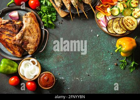 Kebab Kofta fatti in casa, bistecca alla griglia e verdure alla griglia su uno spiedino con verdure e salsa di pomodoro su un piano di pietra scuro. Vista dall'alto, disposizione piatta b Foto Stock