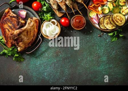 Kebab Kofta fatti in casa, bistecca alla griglia e verdure alla griglia su uno spiedino con verdure e salsa di pomodoro su un piano di pietra scuro. Vista dall'alto, disposizione piatta b Foto Stock