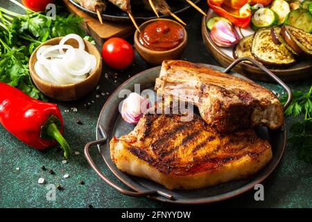 Kebab Kofta fatti in casa, bistecca alla griglia e verdure alla griglia su uno spiedino con verdure e salsa di pomodoro su un piano di pietra scuro. Foto Stock