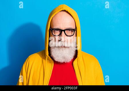 Ritratto di bell'uomo d'affari serio messo a fuoco in occhiali indossare cappuccio fissando isolato su sfondo di colore blu Foto Stock