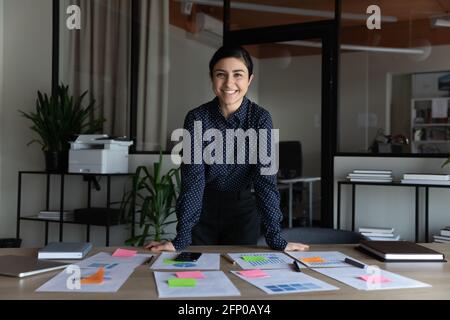 Ritratto di sorridente lavoro di businesswoman indiano con documenti finanziari Foto Stock