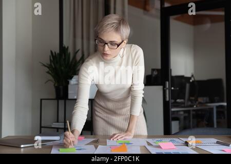 Donna d'affari sicura impegnata a lavorare con documenti finanziari Foto Stock