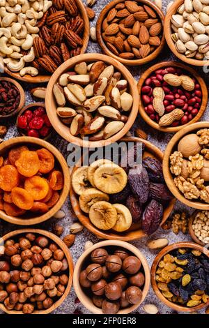 Varie noci e frutta secca in ciotole di legno, vista dall'alto. Foto Stock