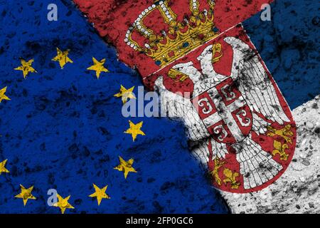 Concetto del rapporto tra l'Unione europea e la Serbia con bandiere dipinte su un muro con una crepa Foto Stock