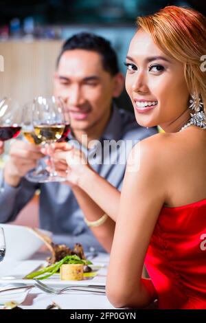 Amici asiatici, due coppie, a pranzo nel ristorante elegante mangiare bene e bere il vino Foto Stock