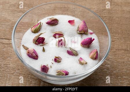 Boccioli di rosa secchi in una tazza di vetro con zucchero bianco per ottenere il sapore e l'odore di rosa Foto Stock