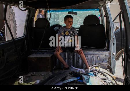 (210520) -- GAZA, 20 maggio 2021 (Xinhua) -- UN ragazzo palestinese si siede all'interno di un veicolo distrutto dopo essere stato colpito da un attacco aereo israeliano nel campo profughi di Jabalia, nel nord della striscia di Gaza, il 20 maggio 2021. (Foto di Rizek Abdeljawad/Xinhua) Foto Stock