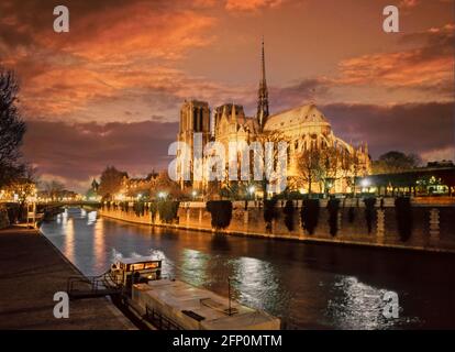 Anni '90 archivistico francese sera tramonto e tramonto cielo oltre illuminata iconica cattedrale storica di Notre Dame e chiatta ormeggiata sulla Senna Parigi Francia UE Foto Stock