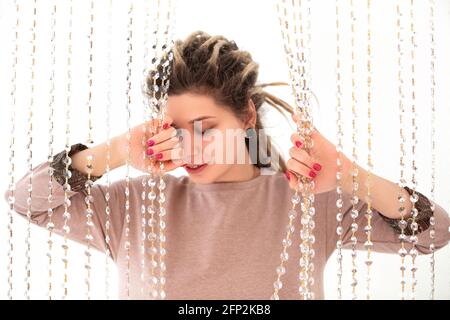 Giovane donna allegra in vestito colorato guardando la fotocamera con i dreadlock sorridenti e agitanti sono isolati su sfondo bianco Foto Stock