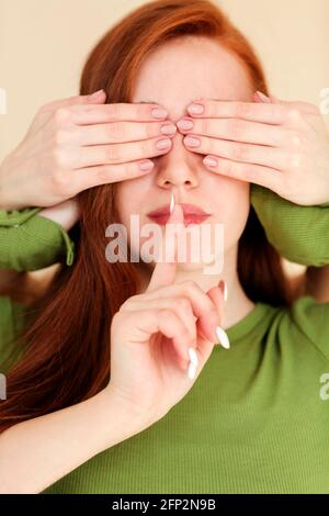 Femmina sorda e cieca con occhi coperti che tengono il dito vicino labbra e chiedere di mantenere il silenzio Foto Stock