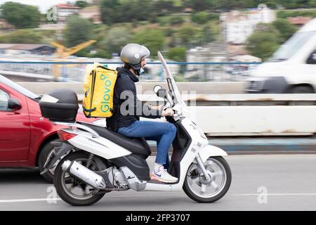 Belgrado, Serbia - 13 maggio 2021: Corriere che lavora per il servizio di consegna del cibo Glovo che guida uno scooter sulla strada urbana sopra il ponte Foto Stock