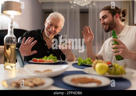 Giovani e anziani che fanno videochiamata e che cenano Foto Stock