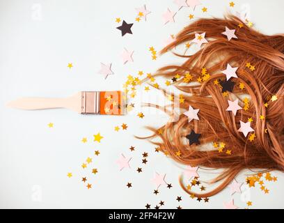 Dall'alto di morbidi capelli setosi su sfondo bianco con spazzolare da parte tutto in confetti sparsi a forma di stella Foto Stock