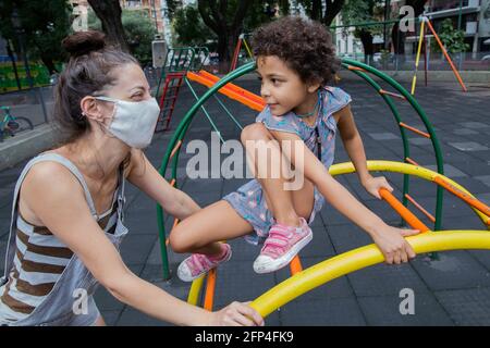 Mamma e figlia si divertiranno al parco giochi all'aperto in una nuova vita normale. Foto Stock