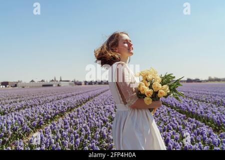 Ritratto a lunghezza intera di donna in piedi sui campi di giacinto Foto Stock