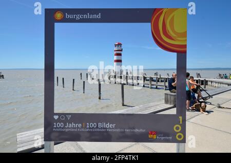 Podersdorf, Austria - 029 maggio 2021: Persone non identificate sul lago Neusiedler con molo, faro e imbarco come segno per 100 anni di appartenenza ad Aus Foto Stock