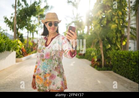 Donna sorridente prende un selfie nel cortile della sua casa. Foto Stock