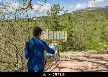 Artista al lavoro sul luogo all'aperto nelle montagne della crimea, dipinge in olio su tela, cavalletto e spazzole, all'aperto nelle montagne della Crimea Foto Stock