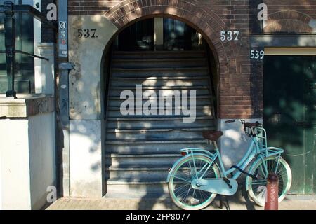 Amsterdam, Paesi Bassi - Giugno 27 2018: Blocco di appartamenti ad Amsterdam, con una bicicletta alla porta d'ingresso. Foto Stock